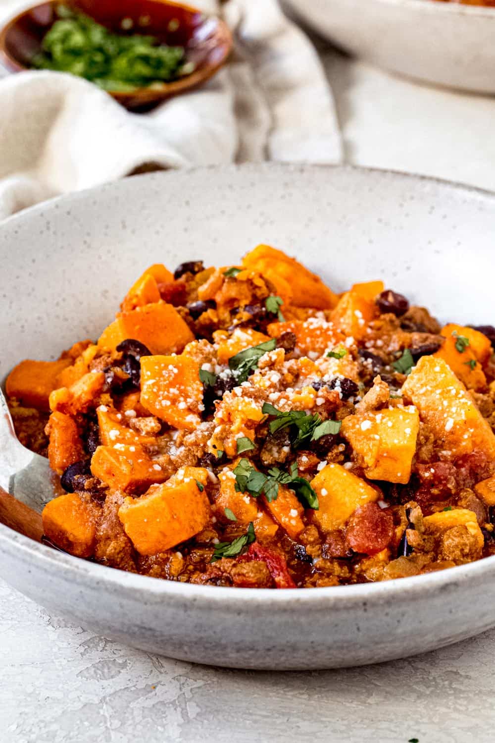 Sweet potato chili topped with parsley in a white bowl.