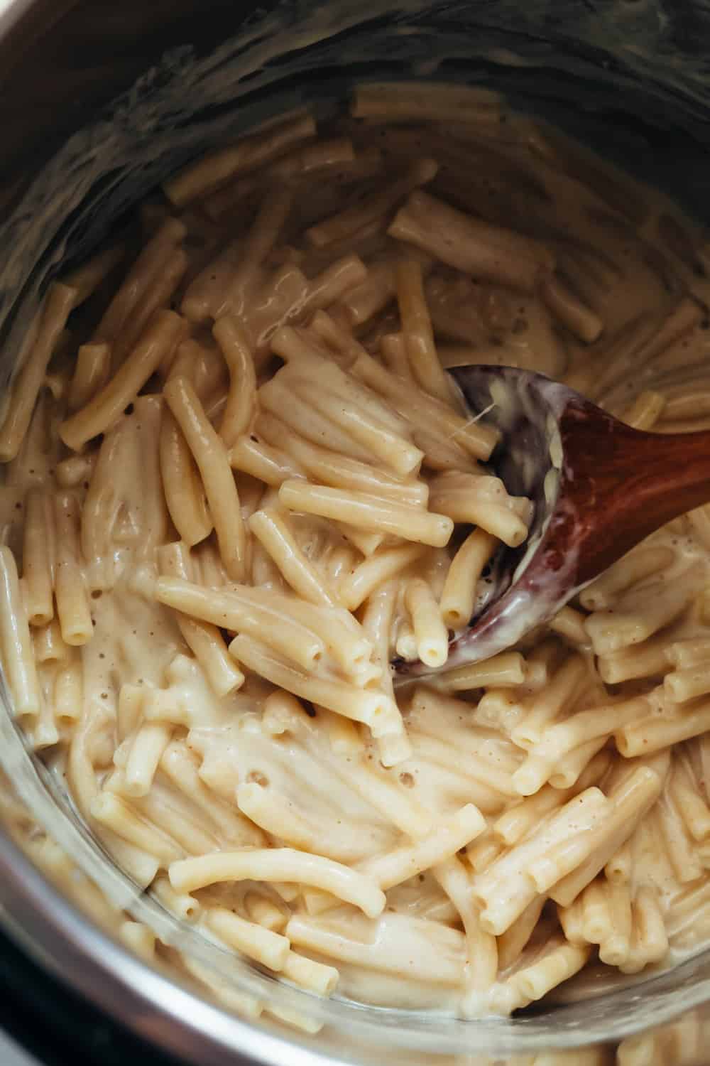 Instant Pot Mac and Cheese ready in the pot with a ladle mixing it