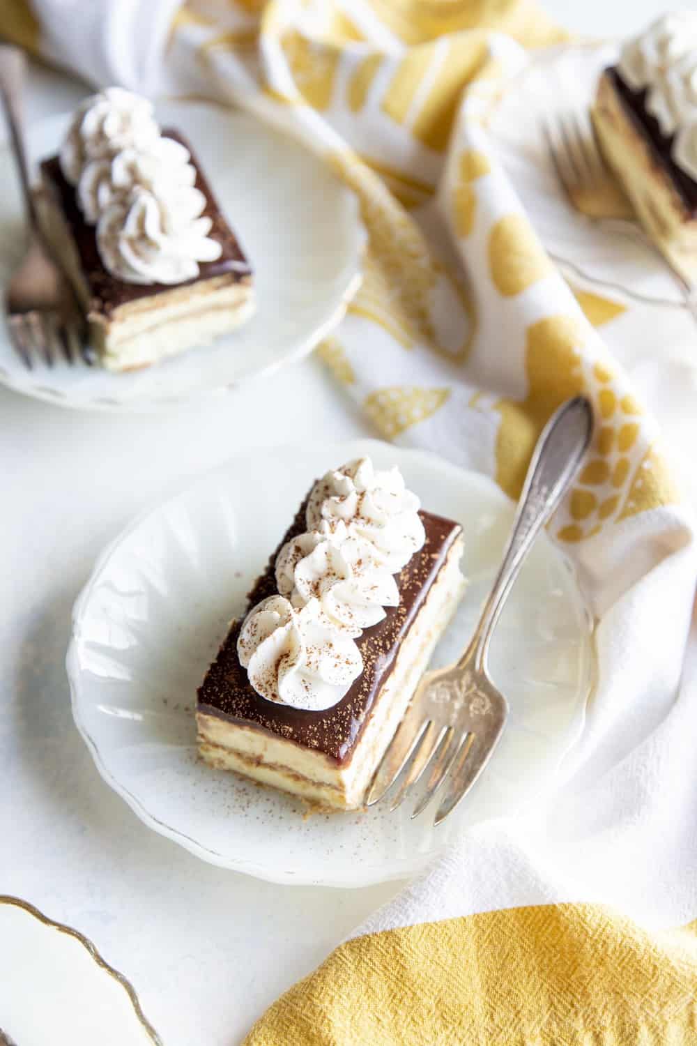 Eclair cakes on white plates with forks.