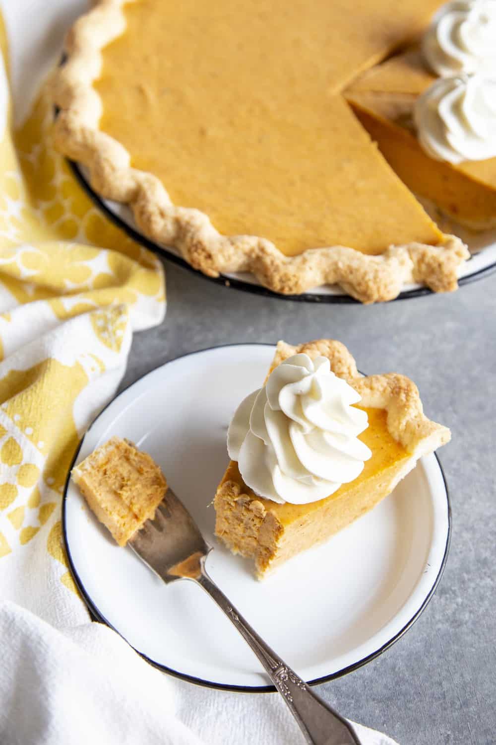 Partial eaten slice of sweet potato pie on a plate next to the pie dish