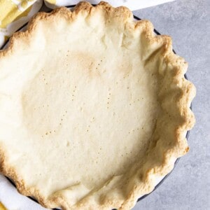 A par-bake pie crust on a gray surface next to a tea towel