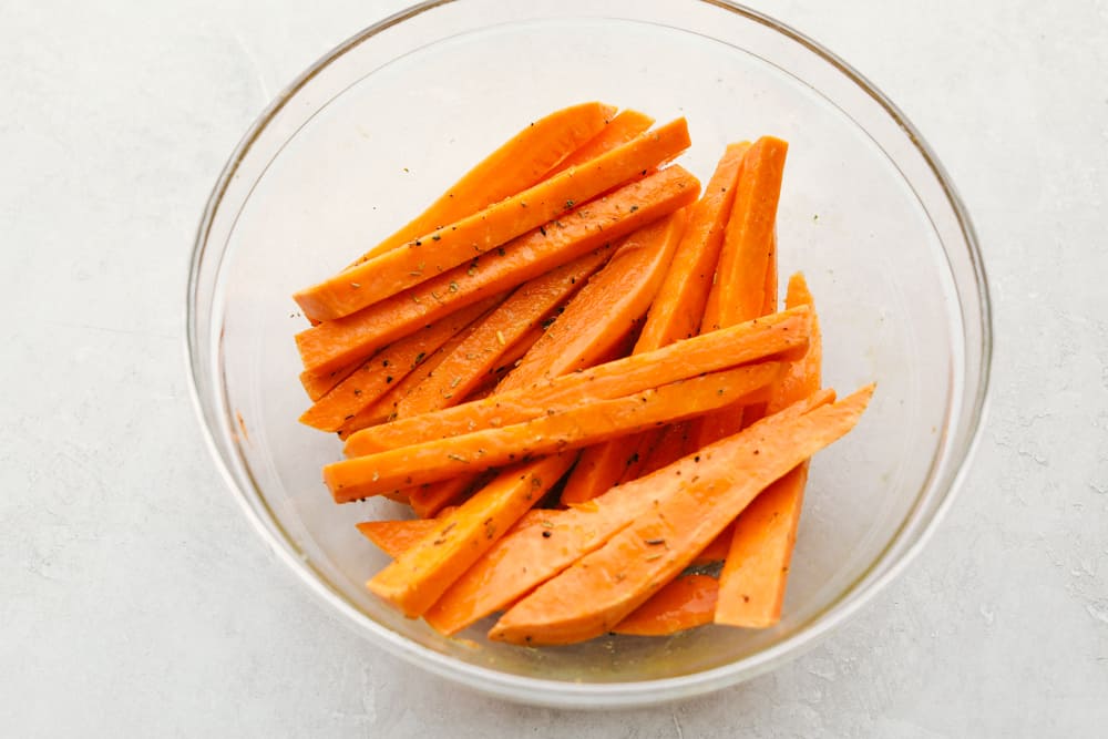 Covering the sweet potato fries with oil and seasonings.