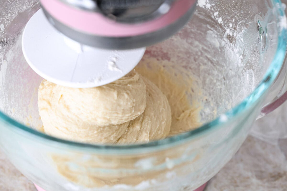 Angle shot of dough being mixed in a stand mixer. 