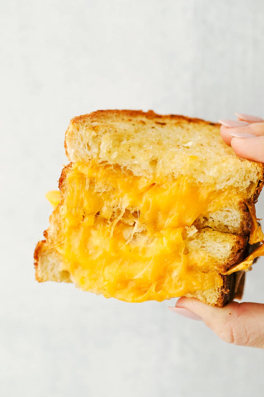 Holding a grilled cheese done in the air fryer cut in half. 