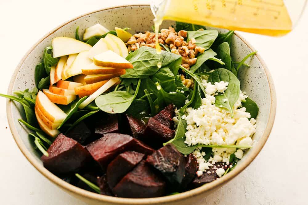 Pouring dressing over the bowl of salad. 