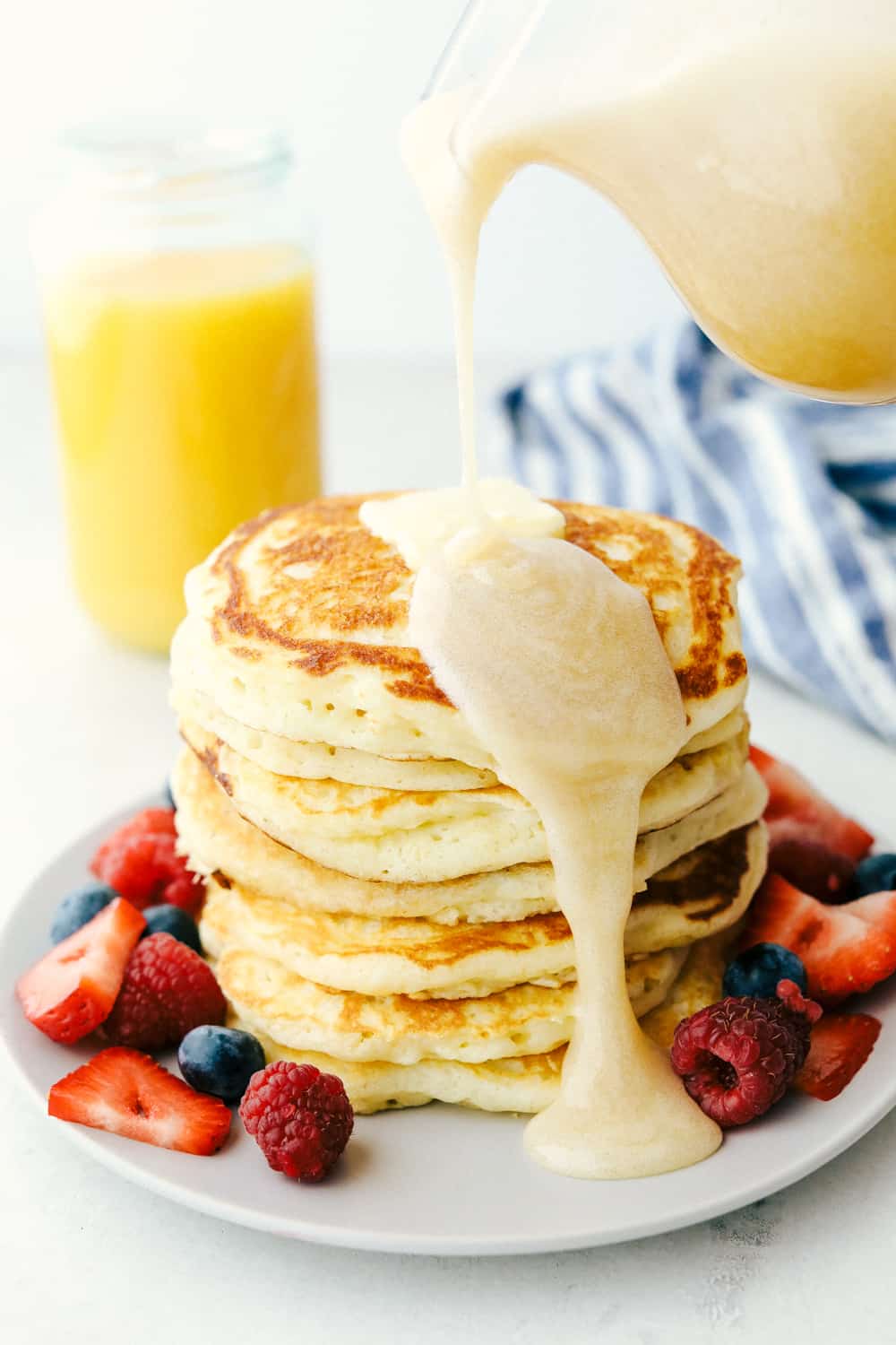 Buttermilk syrup being poured over buttermilk pancakes.