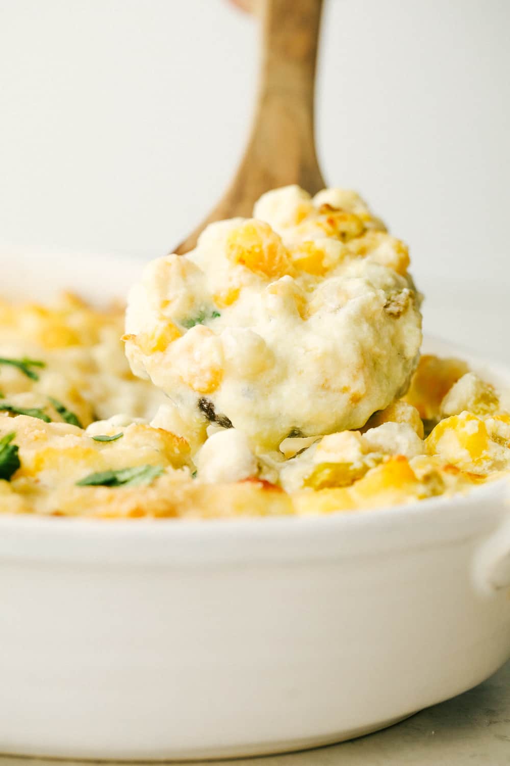 Scooping out creamy cheesy hominy casserole.