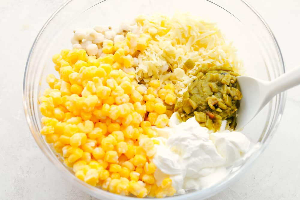 Ingredients for hominy casserole in a glass bowl.