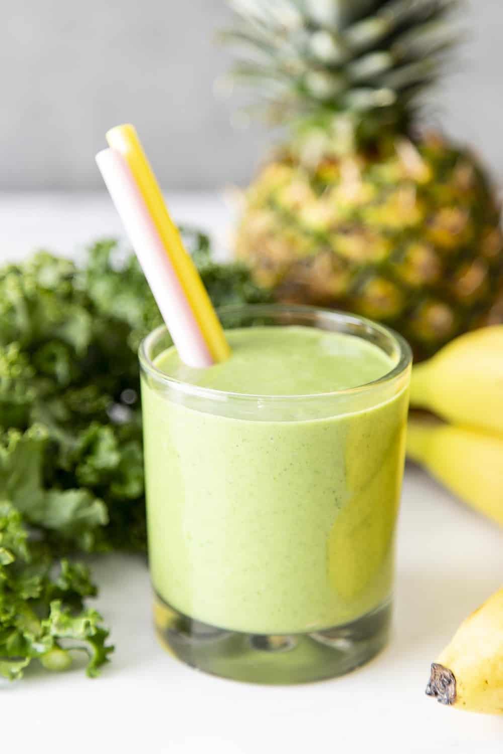 Kale smoothie in a glass surrounded by the ingredients