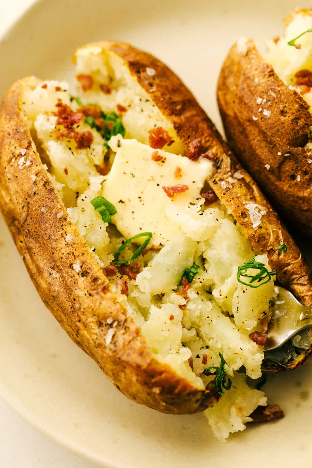 Fluffy potatoes with butter, bacon and chives on a plate. 