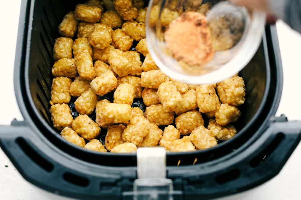 Seasoning frozen tater tots in the air fryer. 