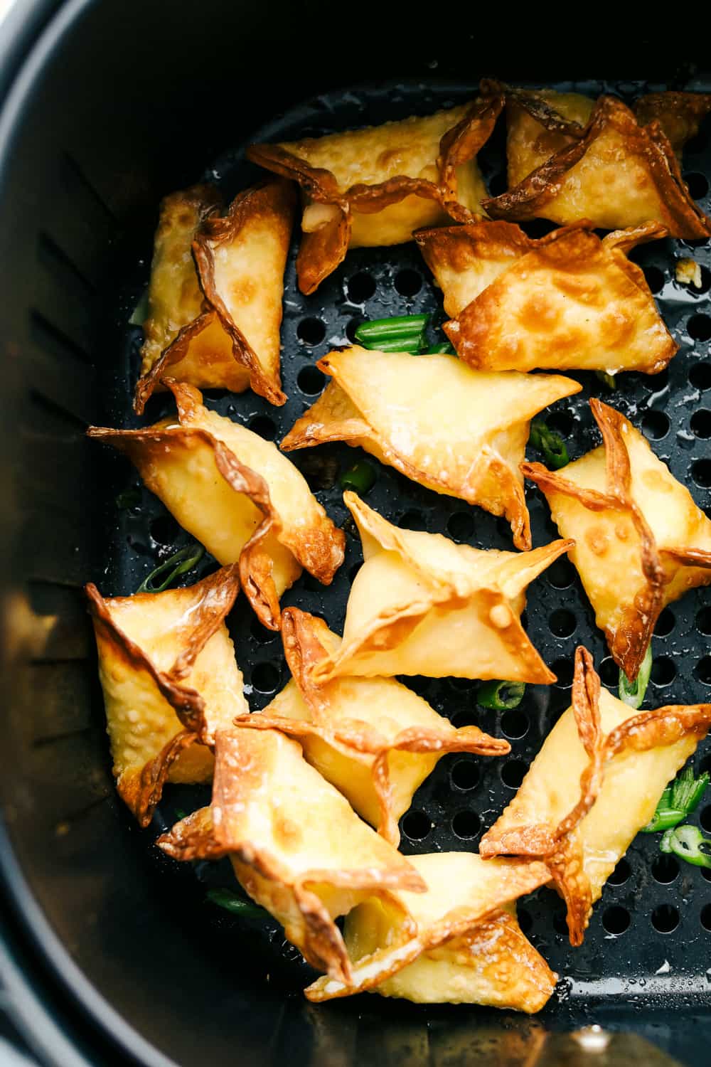 Crispy air fryer wontons in air fryer basket. 