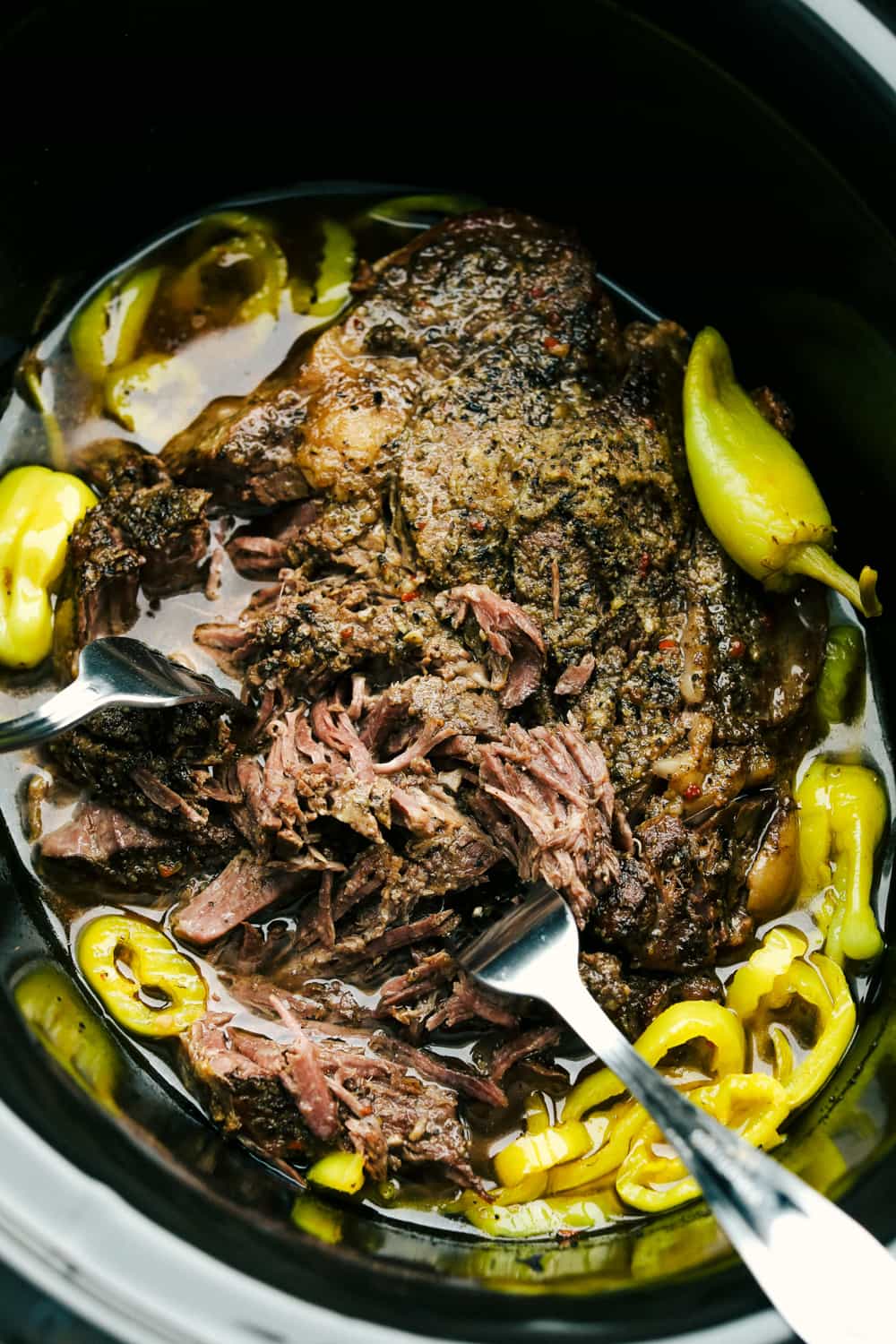 Forks shredding tender Italian Beef. 