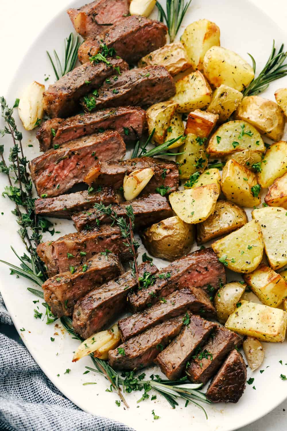 Cut up steak and potatoes on a white plate. 