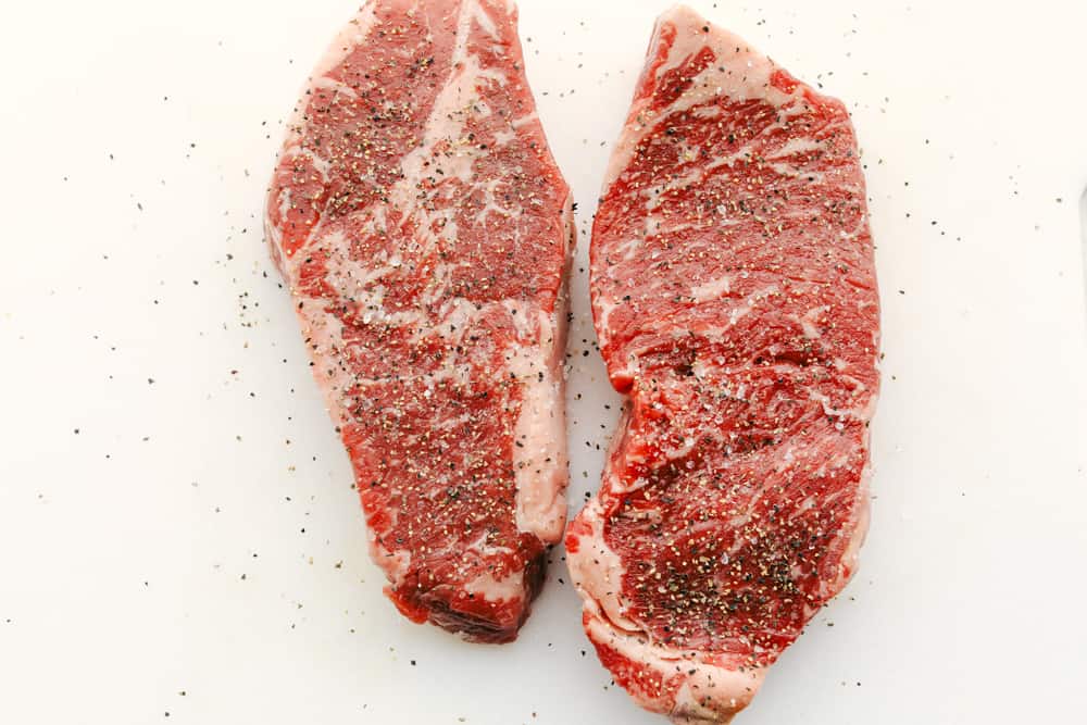 Two steaks seasoned with salt and pepper. 