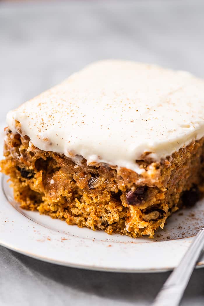 A carrot cake bar on a plate with a fork.