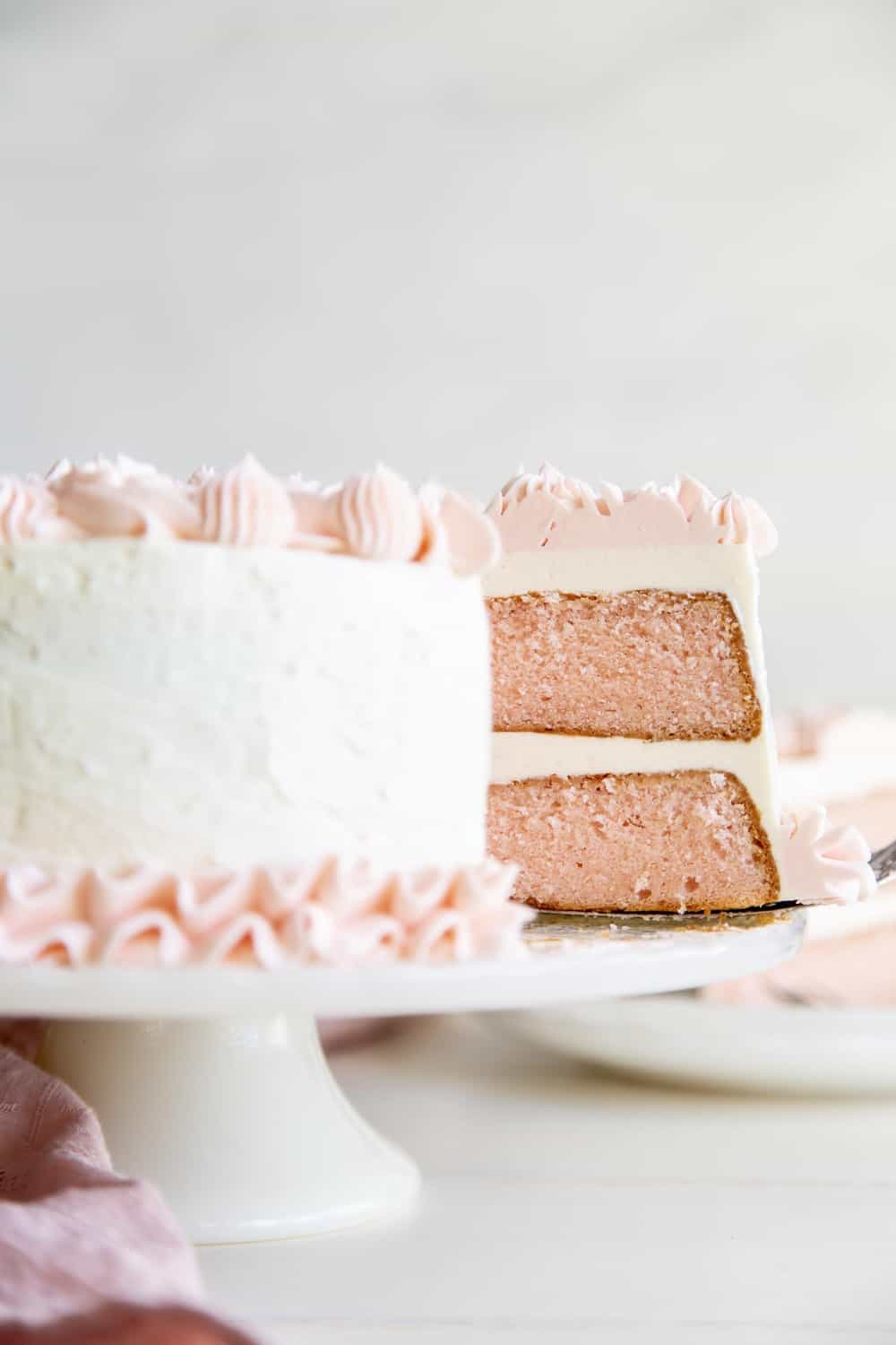 The inside of the pink velvet cake with white frosting and pink frosting flowers. 