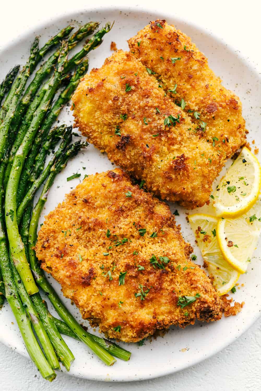 Crispy parmesan air fryer cod with asparagus on a plate. 