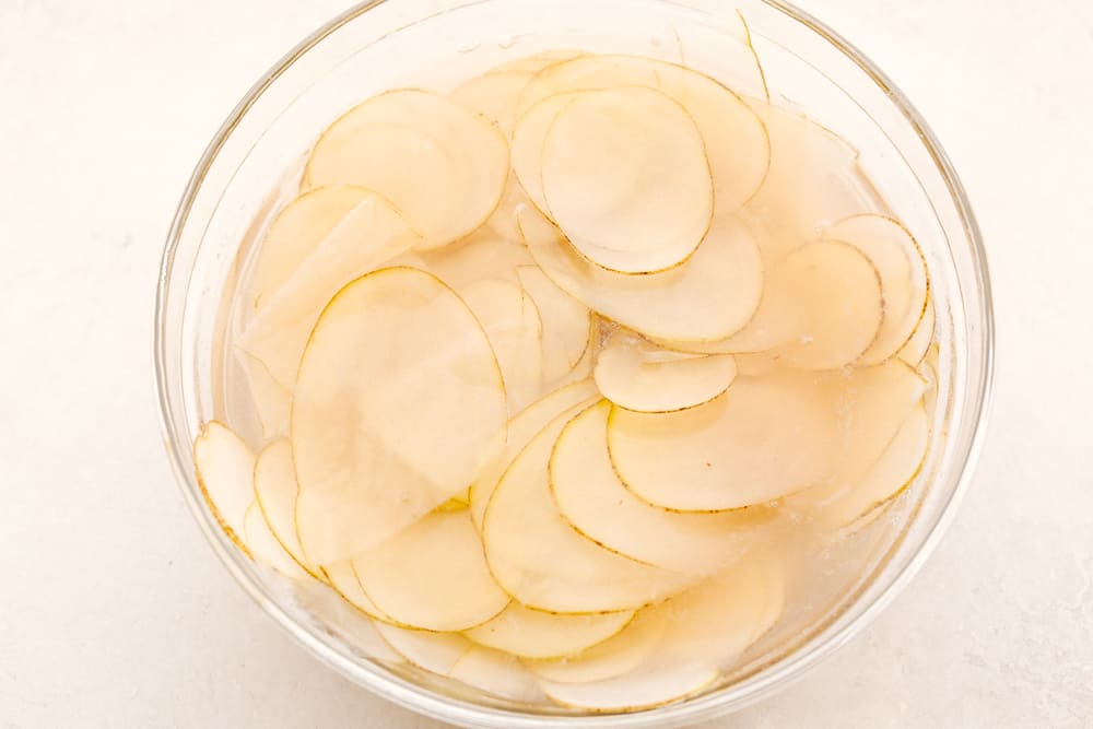 Soaking sliced potatoes in water. 