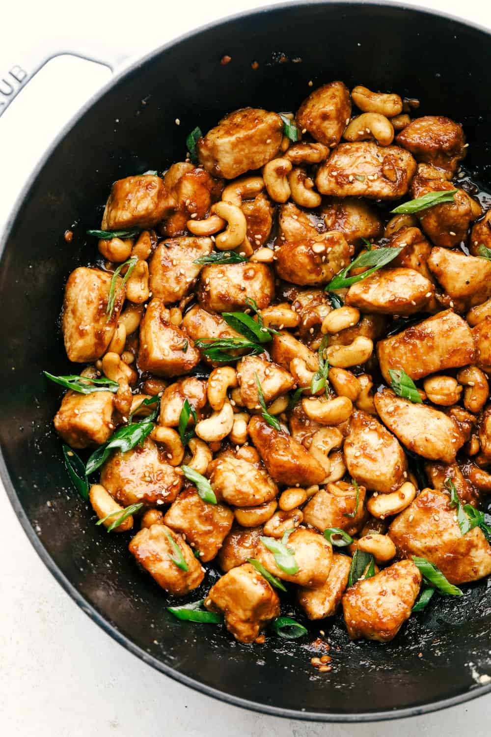 Cashew chicken in a wok with garnish.