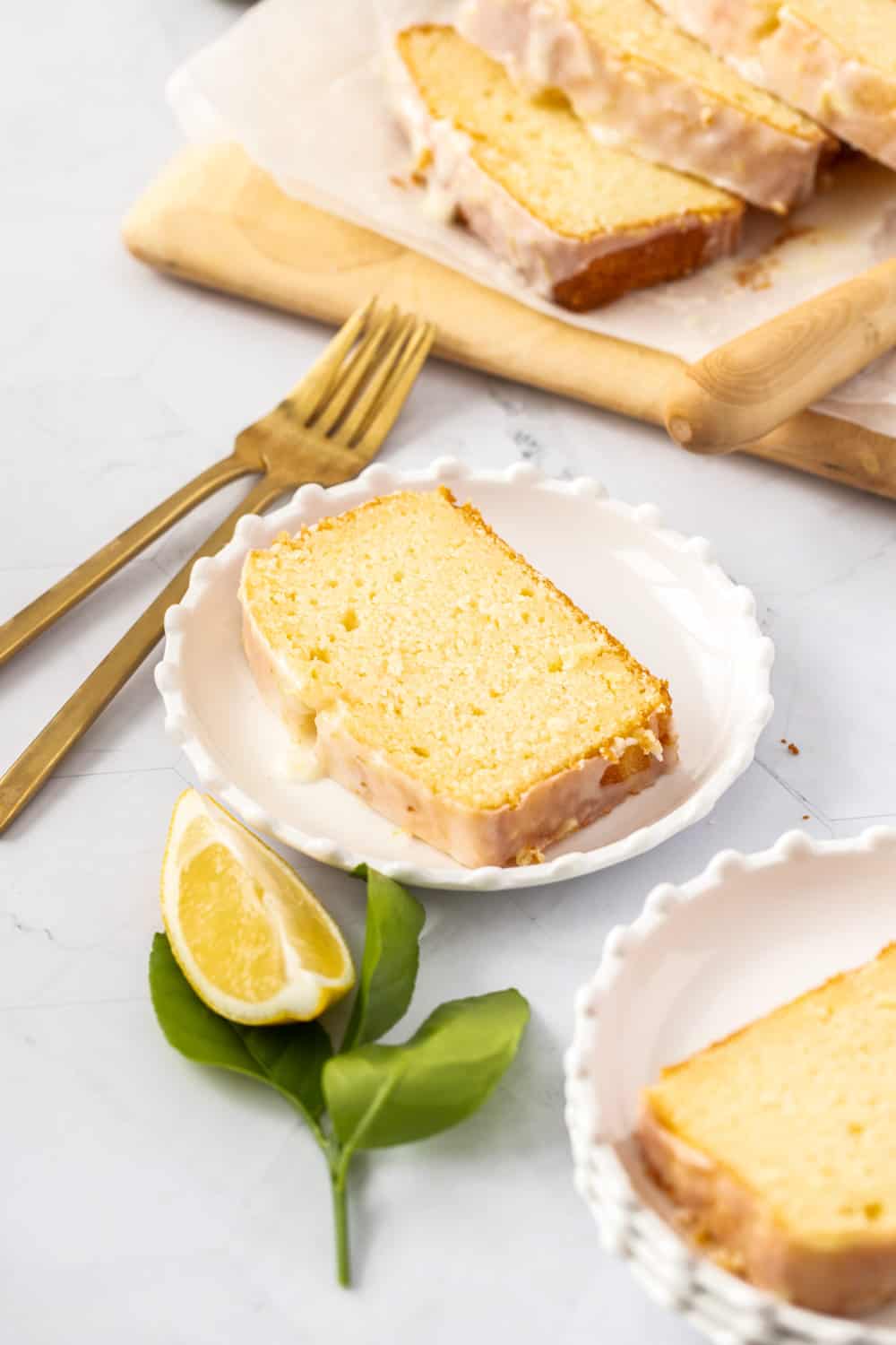 A slice of cake on a white plate with gold fork nearby.