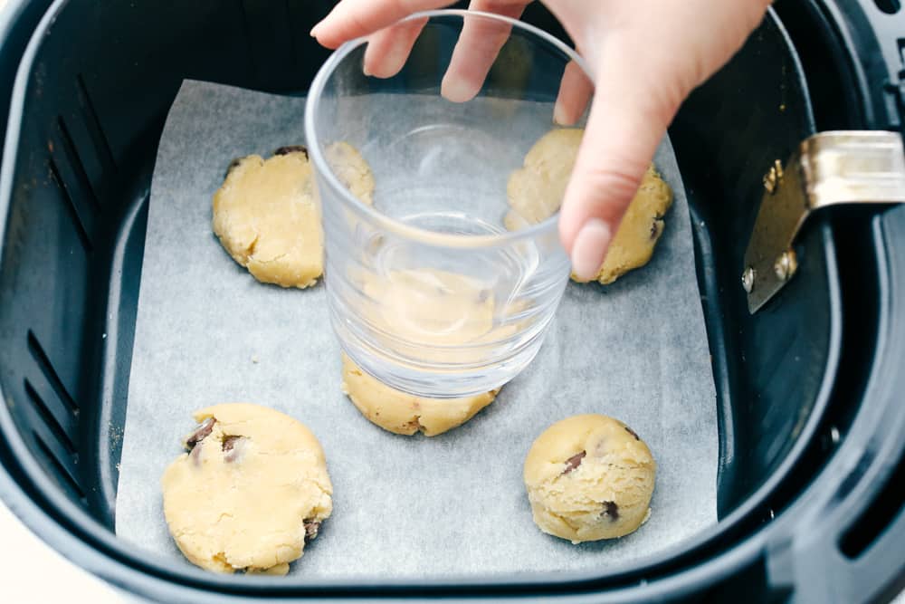 Flattening the cookies in the air fryer with a glass. 