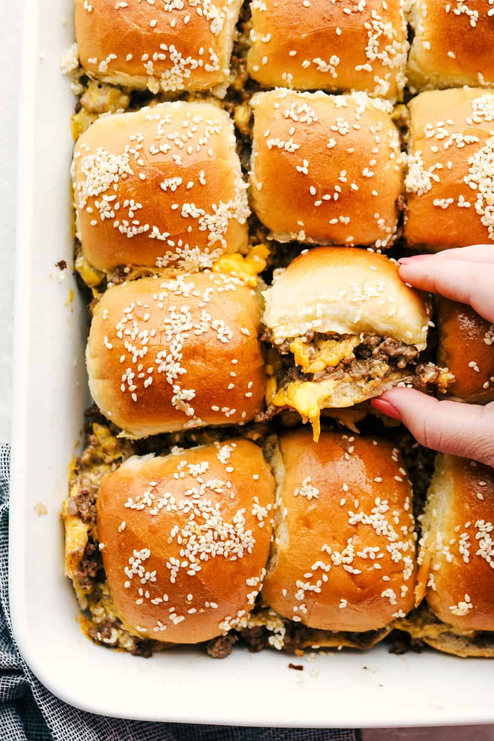 Grabbing a cheeseburger slider out of the pan.