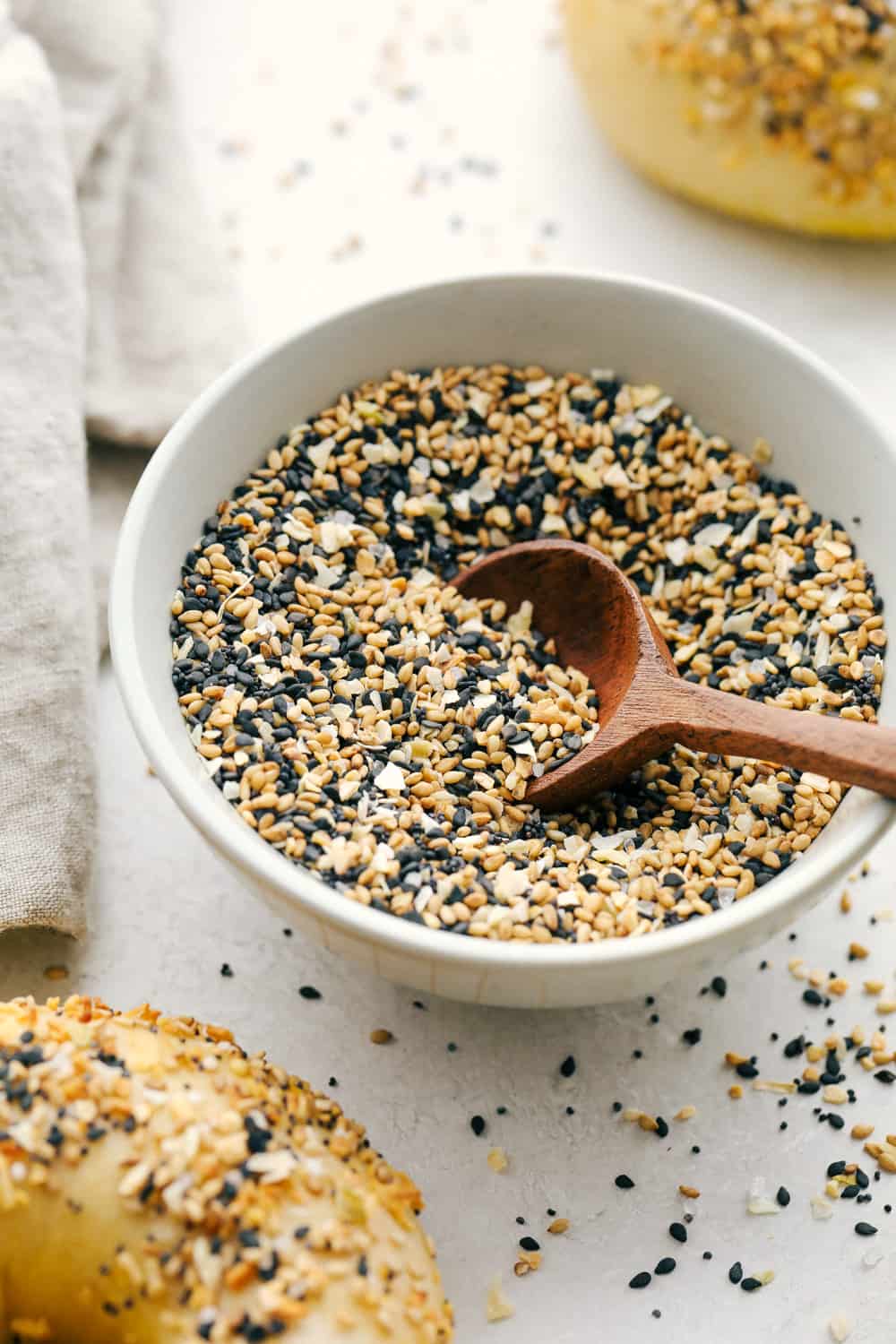 A Bowl full of Everything but the bagel seasoning next to bagels. 