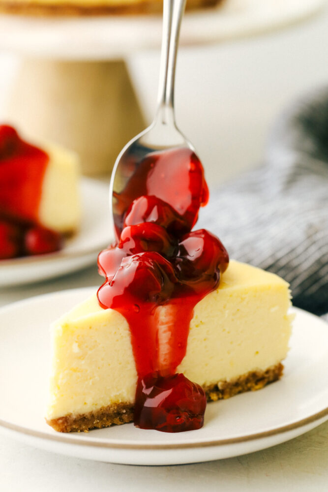 Cherries being put on top of the cheesecake. 