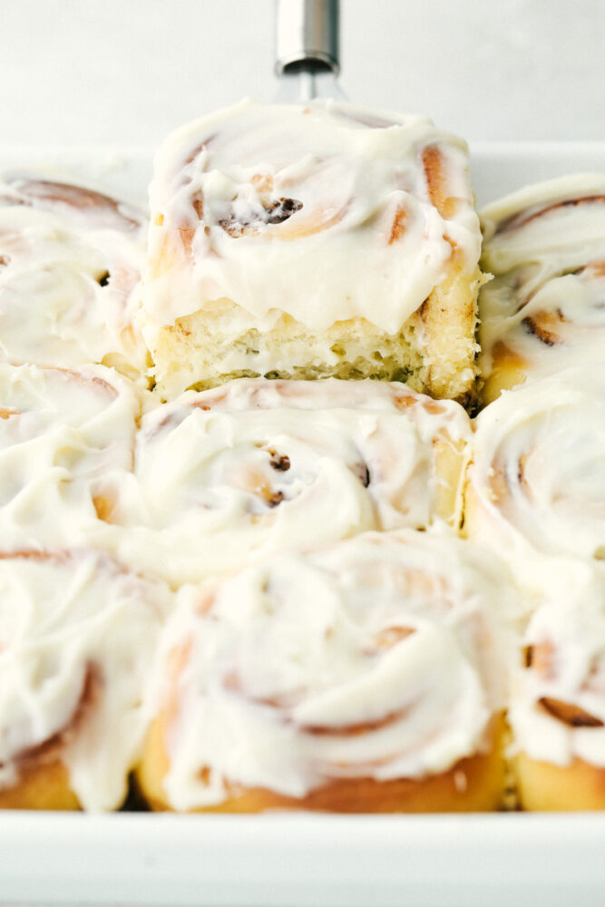 Scooping a cinnamon roll out of the pan. 