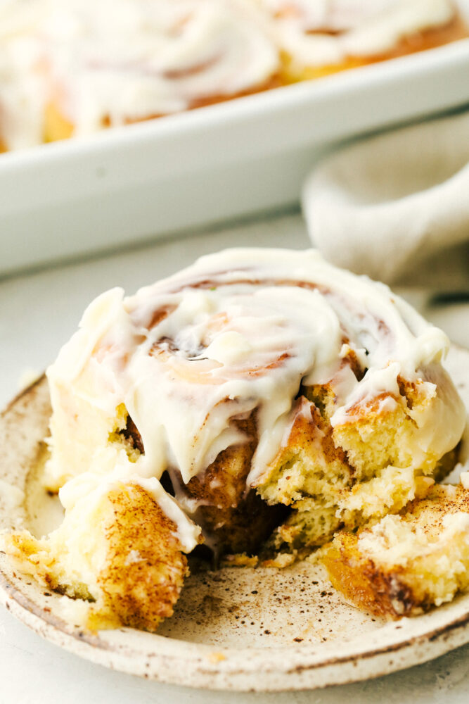 Cinnamon roll on a plate half eaten. 