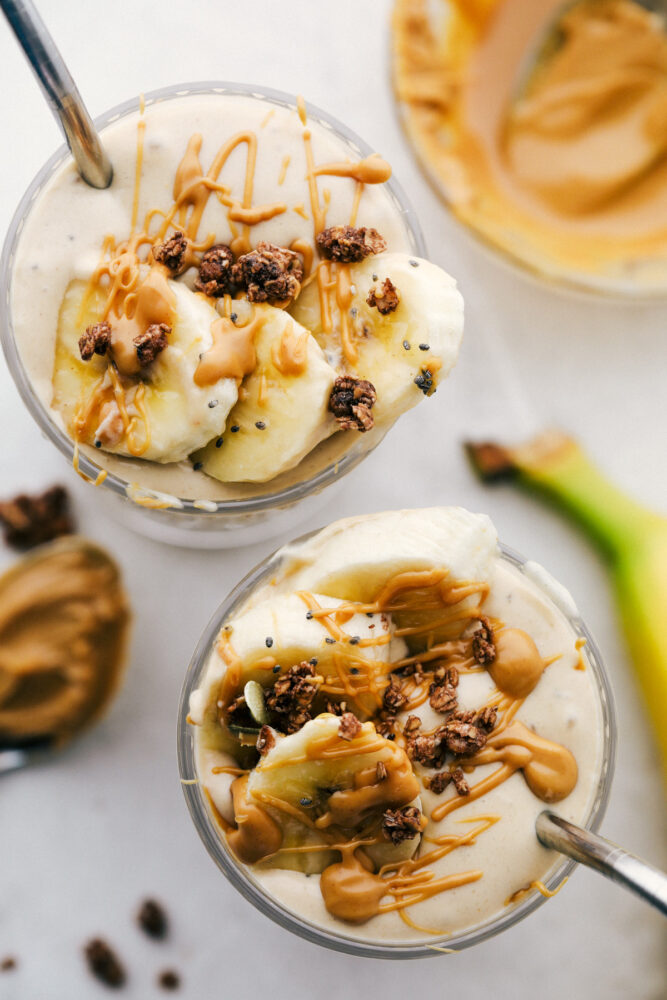 The top of a banana smoothie with fresh cut bananas with a straw in a glass cup.