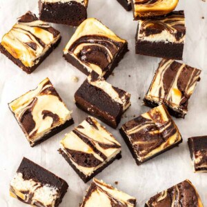 Top down view of a batch of cheesecake topped brownies on a sheet of baking paper.