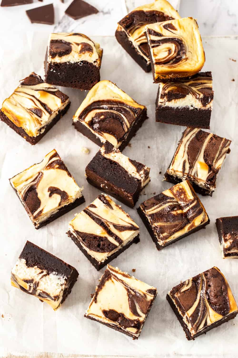 Top down view of a batch of cheesecake topped brownies on a sheet of baking paper.