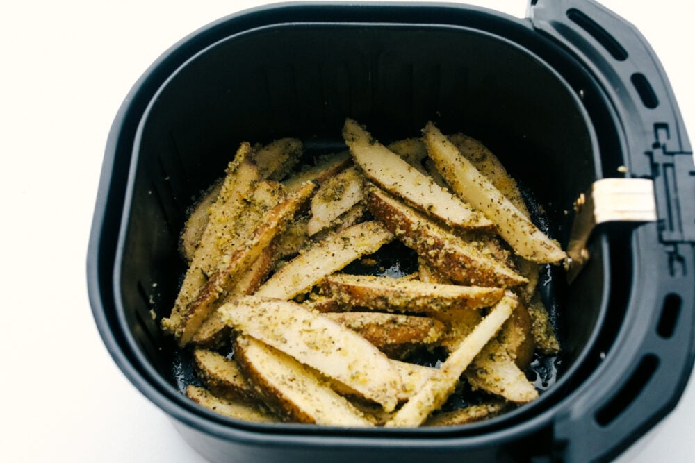 Air fryer basket full of wedges ready to cook. 