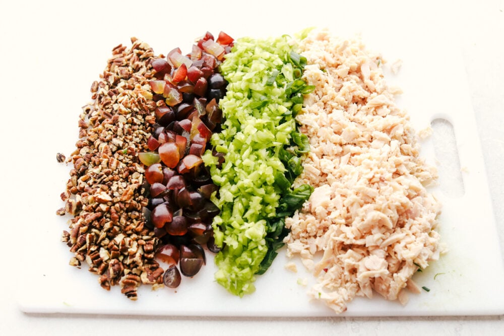 Pecans, grapes, celery, onions and chicken on a cutting board. 