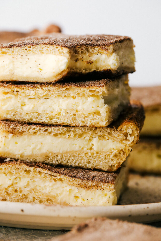 Churro cheesecake bars stacked with a bite out of them. 