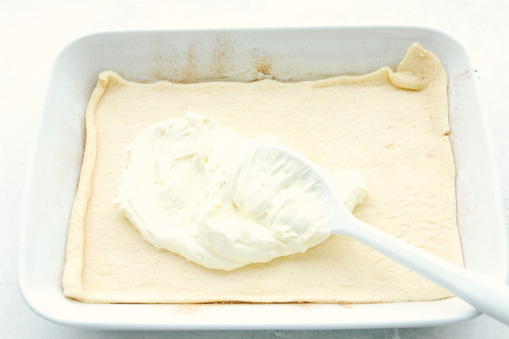 Spreading the cream cheese filling over the crescent dough. 