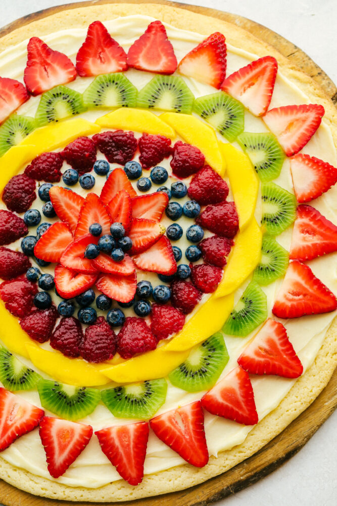 Fruit pizza with fresh fruit cut up and frosting underneath. 