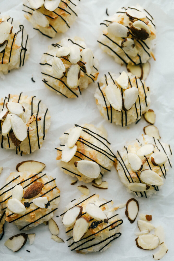 Almond Joy Macaroons on a cookie sheet with drizzle and almonds. 