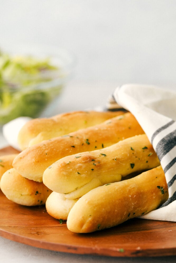 A bunch of breadsticks wrapped in a towel ready to eat. 