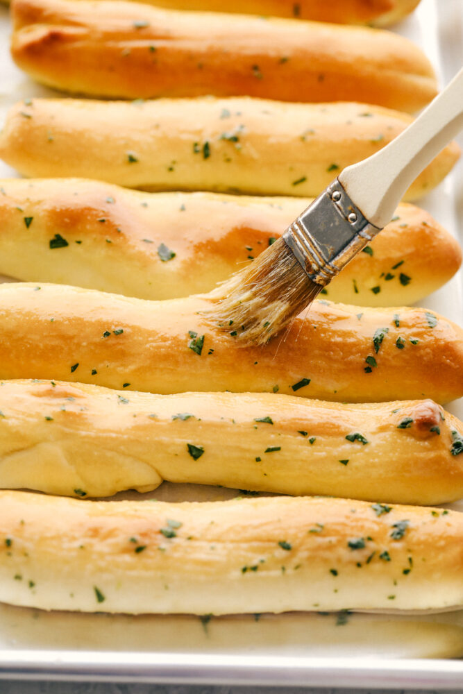 Brushing on more buttery seasoning after they have baked. 