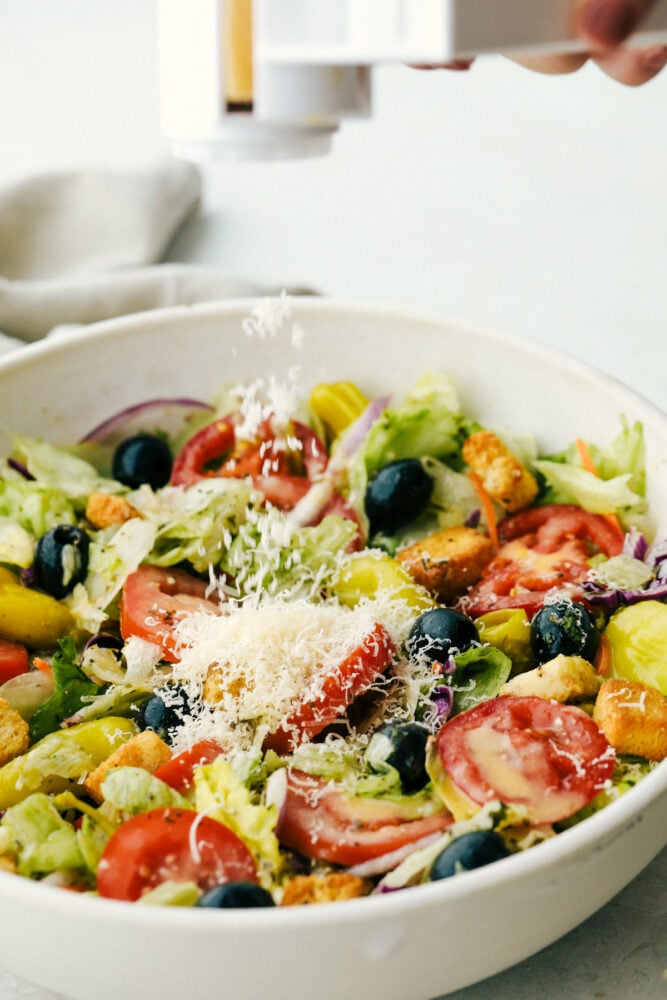 Adding Cheese to a bowl of salad. 