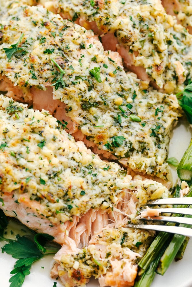 Using a fork to flake off a bite of salmon crusted with parmesan and garlic. 