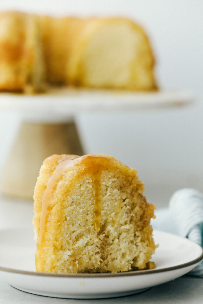 Rum cake slice on plate with rum sauce on top. 