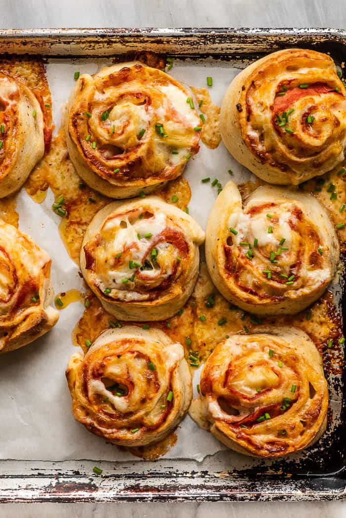 Ham and pineapple pizza pinwheels on a baking sheet.