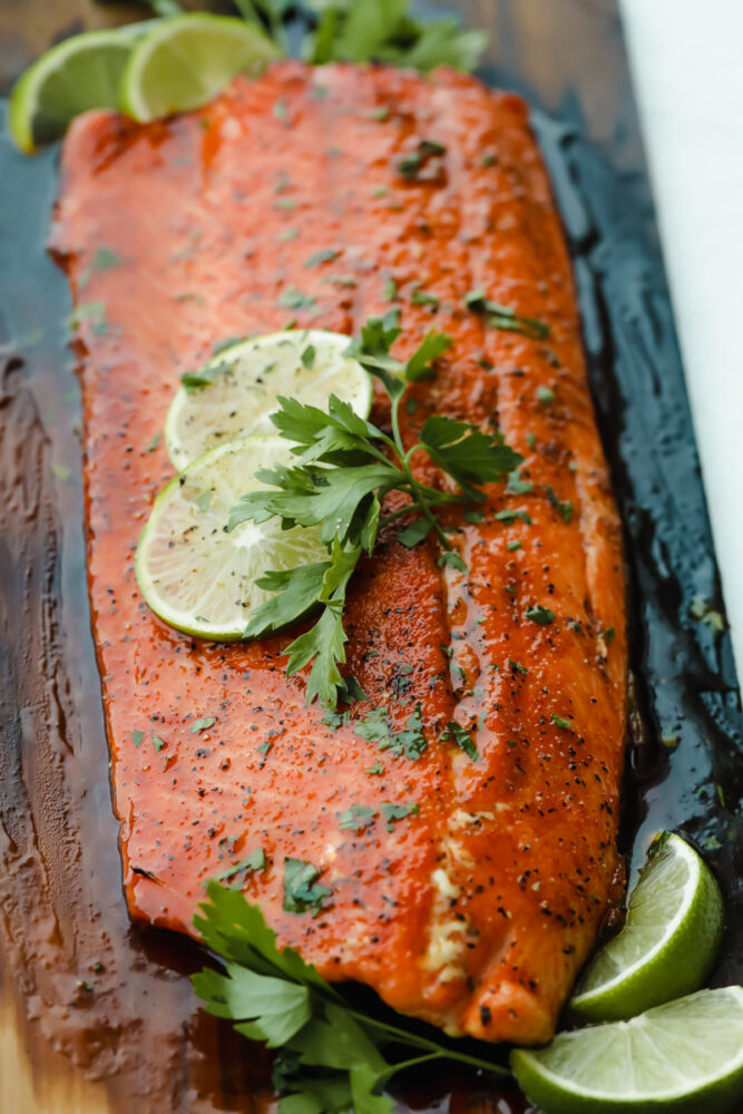 Grilled salmon on cedar plank with lime garnish.