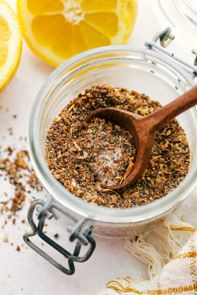 Lemon pepper in a glass jar with a wooden spoon. 