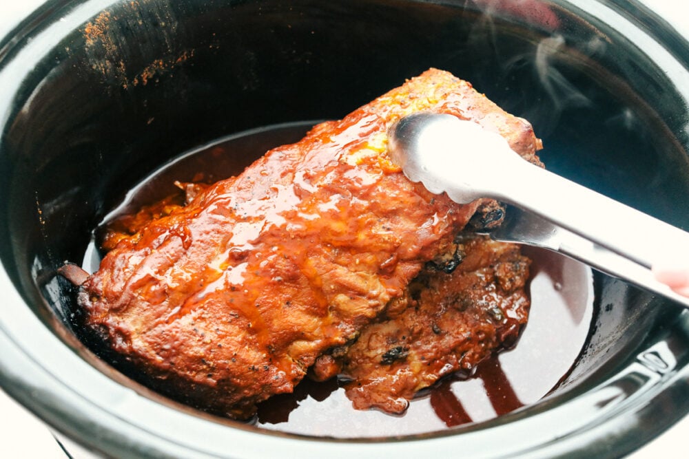 Removing the cooked ribs from the slow cooker. 