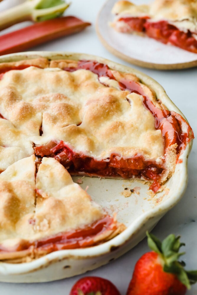 Strawberry rhubarb pie with piece taken out of it